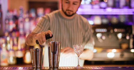 Cocktail making. Bartender mixing. Man spraying pink flavor to drink in metal shaker. Professional preparing alcoholic beverage in pub.
