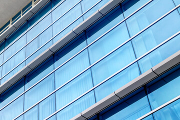Obraz premium Modern glass building facade with blue windows reflecting sky