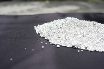A pile of sparkling pure silver grains, refined to 99.99% perfection, sparkle under the light. Each tiny grain reflects clarity and value.
