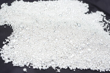 A pile of sparkling pure silver grains, refined to 99.99% perfection, sparkle under the light. Each tiny grain reflects clarity and value.