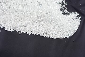 A pile of sparkling pure silver grains, refined to 99.99% perfection, sparkle under the light. Each tiny grain reflects clarity and value.