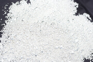 A pile of sparkling pure silver grains, refined to 99.99% perfection, sparkle under the light. Each tiny grain reflects clarity and value.
