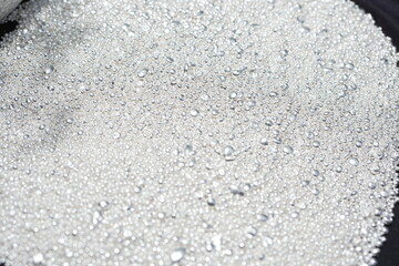 A pile of sparkling pure silver grains, refined to 99.99% perfection, sparkle under the light. Each tiny grain reflects clarity and value.