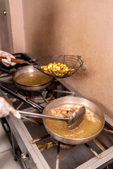 Woman preparing fried food in restaurant kitchen