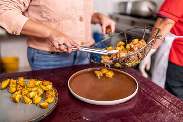 Woman preparing fried chicken and potato in small restaurant kitchen