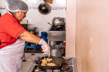 Woman preparing fried food in restaurant kitchen