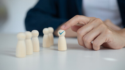 Hand pointing at a wooden figure with a check mark, symbol of recruitment and employee selection,...