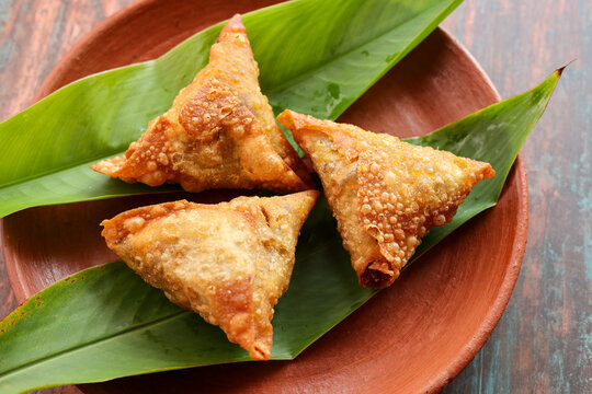 Samosa crunchy triangular shaped wraps stuffed with spicy vegetables. Cocktail mini triangle Kerala samosa made using patti or strip. Popular home made snack from India
