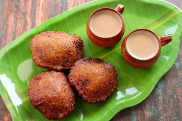 Neyyappam is a rice based kerala snack fried in ghee Famous Indian snack and Traditional kerala snack item. Crispy and tasty snack. Rice pancakes fried in ghee made of jaggery banana leaf side view