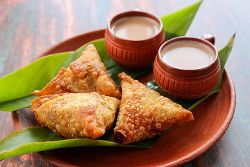 Samosa crunchy triangular shaped wraps stuffed with spicy vegetables. Cocktail mini triangle Kerala samosa made using patti or strip. Popular home made snack from India
