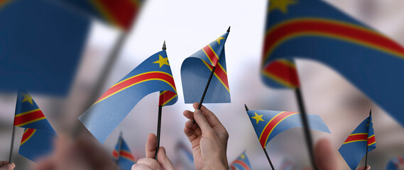 Naklejka premium Democratic Republic of the Congo flags in their hands on a blurred urban background