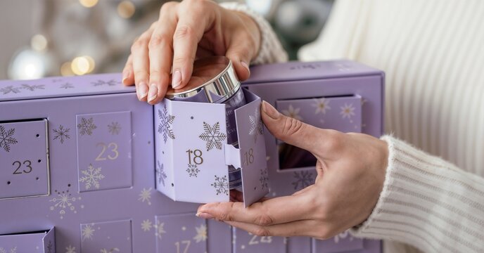 Hands opening advent calendar with purple gift boxes, festive Christmas holiday countdown decoration