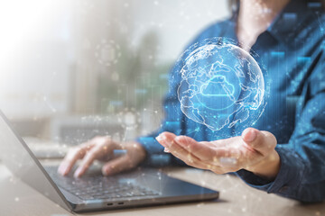 Businessman using laptop with global cloud computing network hologram, symbolizing digital transformation, big data, online storage, and future technology.