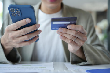 Asian Man paying with credit card on smart phone at office. Male Using Smartphone for Shopping electronic wallet Online