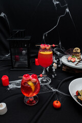 Halloween Cocktails and Treats: A festive table dressed for Halloween, featuring tantalizing...