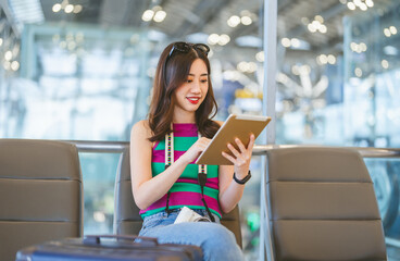 Tourist passenger woman using digital tablet at international airport terminal for depature with...