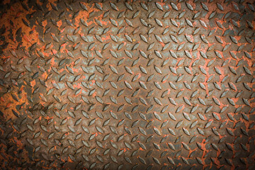 Rusty checkered steel plate surface with grunge texture, industrial metal background showing corrosion, scratches, and rugged weathered details.