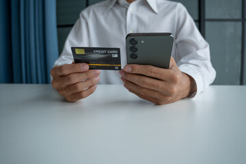 Man holding credit card and phone to pay online