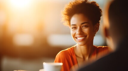 Smiling woman in orange shirt enjoying coffee at sunrise café