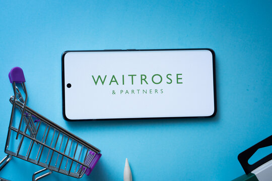 Dhaka, Bangladesh- 03 July 2025: Smartphone displaying Waitrose & Partners logo with shopping cart on a blue background.
