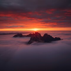 Dramatic sunrise over mountain peaks emerging from thick fog, breathtaking landscape with vibrant red sky, nature scene perfect for background, wallpaper, travel, and adventure inspiration