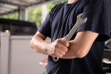 A man with a wrench is ready to do some basic car maintenance.