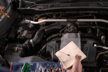 A man is wiping the oil dipstick to make sure it's ready.