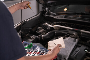 A man is wiping the oil dipstick to make sure it's ready.