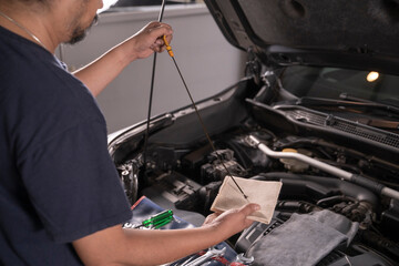 A man is wiping the oil dipstick to make sure it's ready.