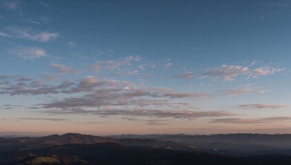 Obraz premium A serene vista of a mountain range bathed in the soft, pastel hues of a tranquil sunrise.