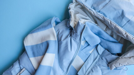 Baby blue winter clothing set on a light blue background, top view.