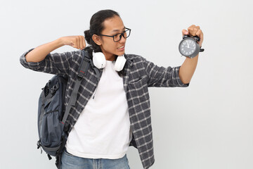 Asian male student wearing casual clothes, backpack, headphones around his neck, showing his alarm...
