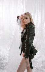 Beautiful woman in black leather jacket on plastic background.