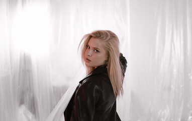 Beautiful woman in black leather jacket on plastic background.