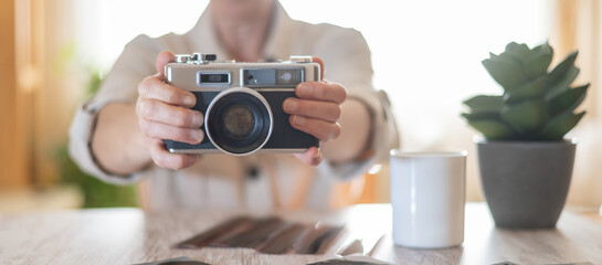 Person holding a retro film camera, showcasing the classic technology and creative process of...