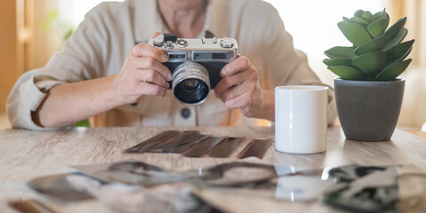 Woman focusing a classic analog camera, preserving cherished memories as film negatives and old...