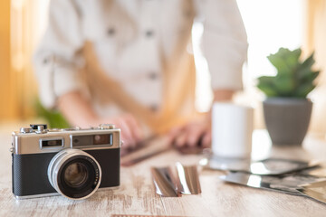 Photographer's hands blurred in background arranging film negatives and prints beside a vintage...
