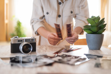 Person examining developed film negatives from a classic camera, reliving memories and enjoying the...