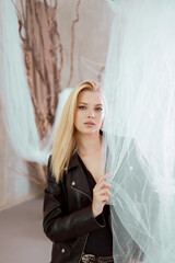 Portrait of a beautiful woman in a leather jacket near the curtain.
