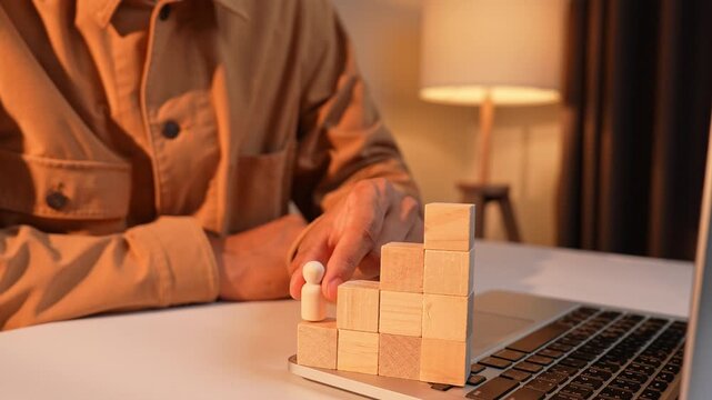 An HR manager moves a wooden figure from the top of stacked blocks to the lowest level, symbolizing employee reassignment, workforce restructuring, talent management, career transitions, strategic.
