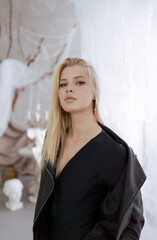 Portrait of a beautiful woman in a leather jacket near the curtain.