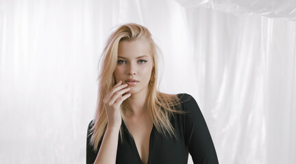 Portrait of a very beautiful blonde in a black dress on an airy background.