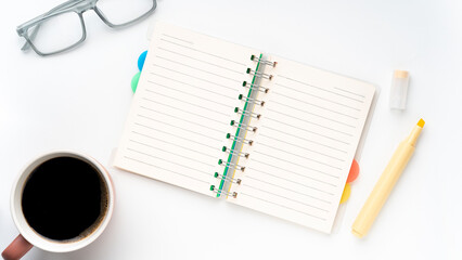 Plan your success with this bright workspace featuring a notebook, glasses, coffee, and a highlighter for a productive day ahead