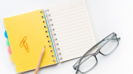Stay organized with a vibrant yellow notebook, pencil, and stylish glasses perfect for planning, journaling, and creative projects at the office or home