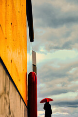 曇天の空を眺める赤い傘の女性