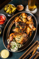 Grilled chicken platter with roasted potatoes and various sauces.
