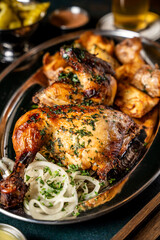 Grilled chicken and roasted potatoes on a metal platter.