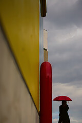 曇天を見て雨を予感する赤い傘の女性