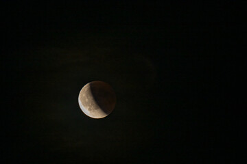 Lunar eclipse beginning close-up right corner sun begins to come on top of moon lunar eclipse black background at night