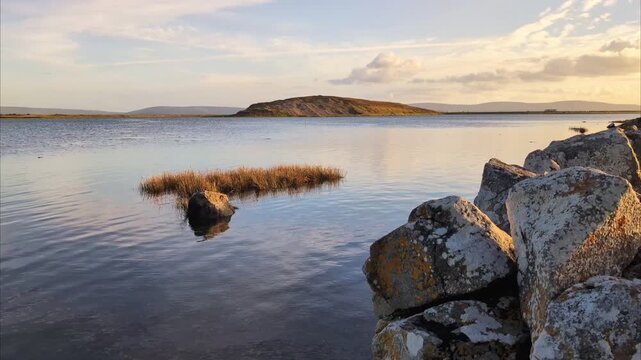Scenic Coastal Landscape of Silverstrand Beach in Galway Ireland featuring Golden Sunset Light over Calm Atlantic Waters and Wild Grasses, adventure travel backround